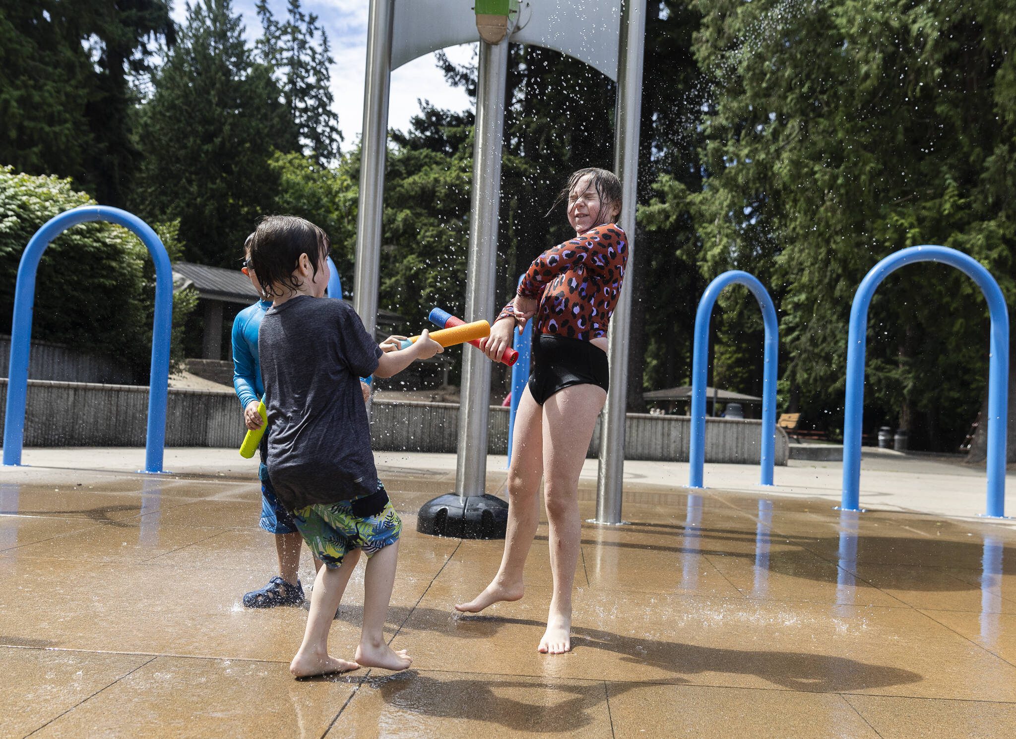 Raven Rutten, 5, left, sprays his sister Neko Rutten, 8, right, with a foam water blaster while they play in the water at the Hazel Miller Spray Park on Monday, July 14, 2025 in Edmonds, Washington. (Olivia Vanni / The Herald)