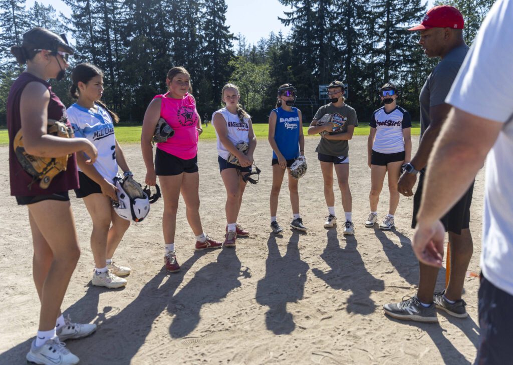 Mill Creek Little League softball infield players listen to their coach before running drills on Wednesday, July 16, 2025 in Mill Creek, Washington. (Olivia Vanni / The Herald)
