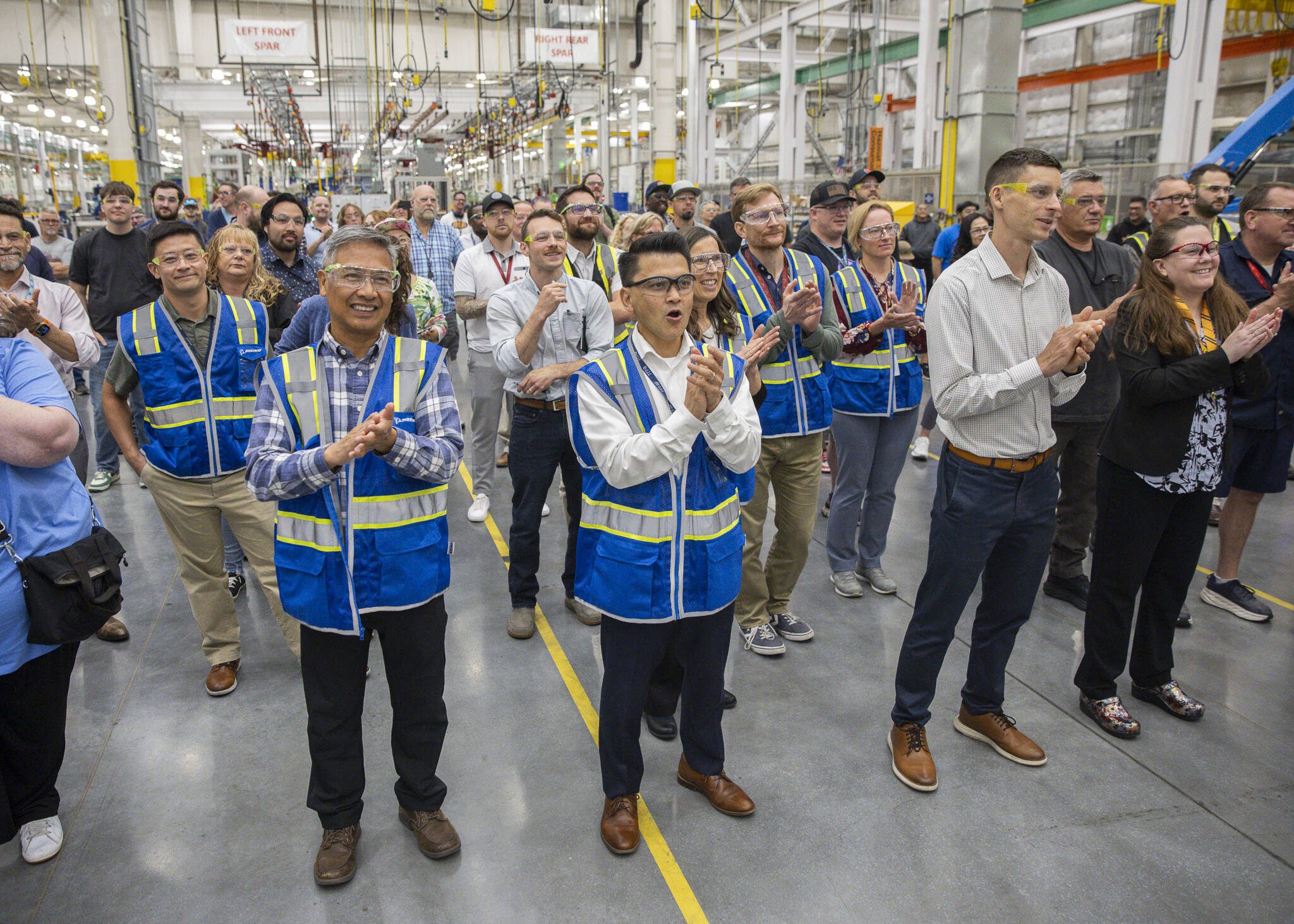 Richard Wong, center, the 777X wing engineering senior manager, cheers as the first hole is drilled in the 777-8 Freighter wing spar on Monday, July 21, 2025 in Everett, Washington. (Olivia Vanni / The Herald)
