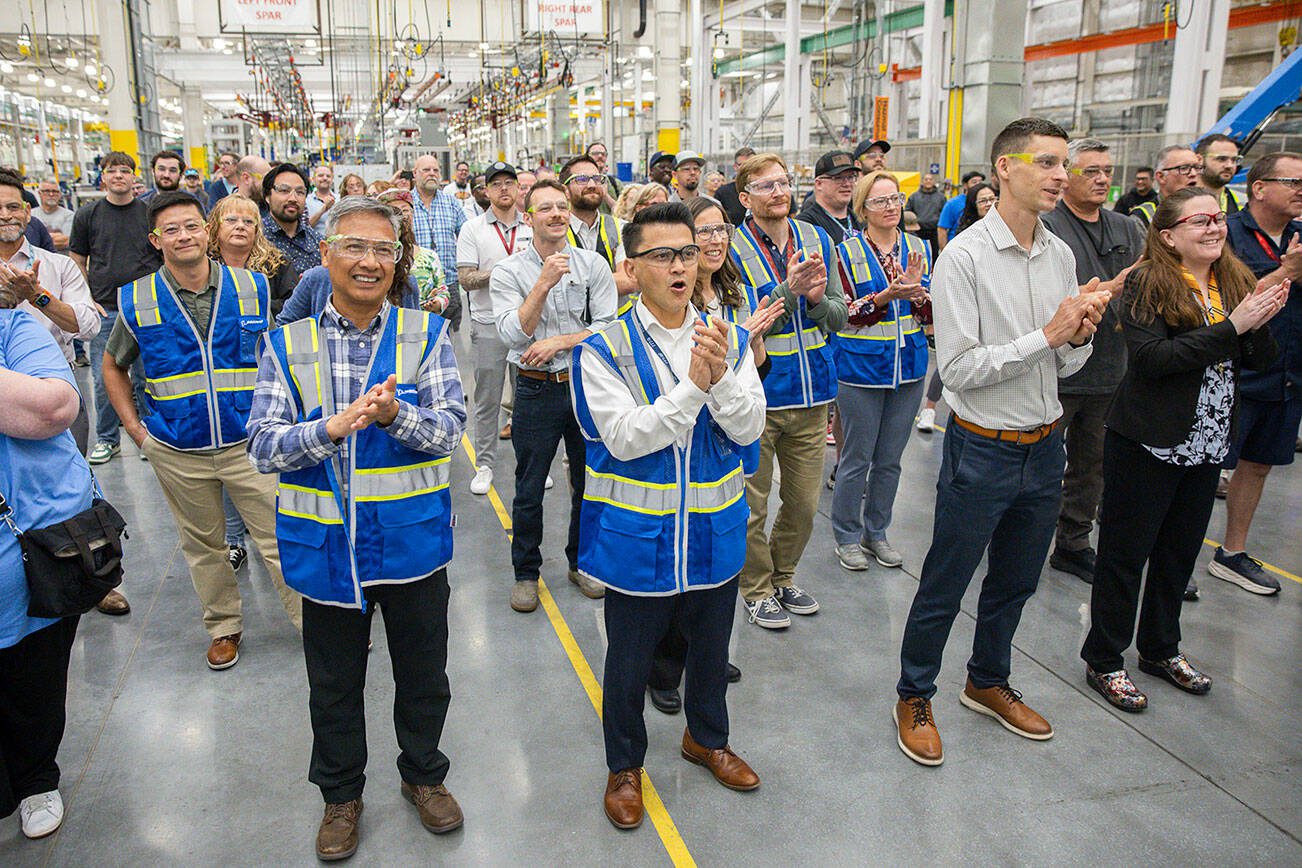 Richard Wong, center, the 777-X wing engineering senior manager, cheers as the first hole is drilled in the 777-8 Freighter wing spar on Monday, July 21, 2025 in Everett, Washington. (Olivia Vanni / The Herald)
