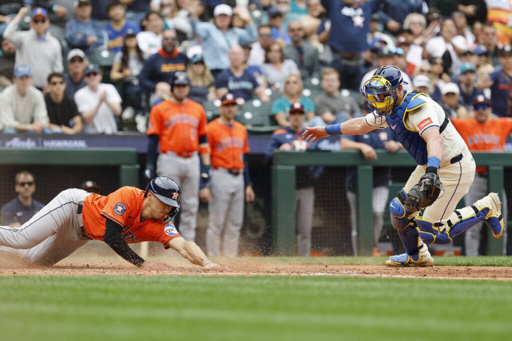Shay Whitcomb (10) of the Houston Astros looks to avoid Mitch Garver (18) of the Seattle Mariners tag at home plate to score off of Cam Smith&rsquo;s two-run RBI double during the fifth inning against the Seattle Mariners at T-Mobile Park on Sunday, July 20, 2025, in Seattle. (Alika Jenner / Getty Images / Tribune News Services)
