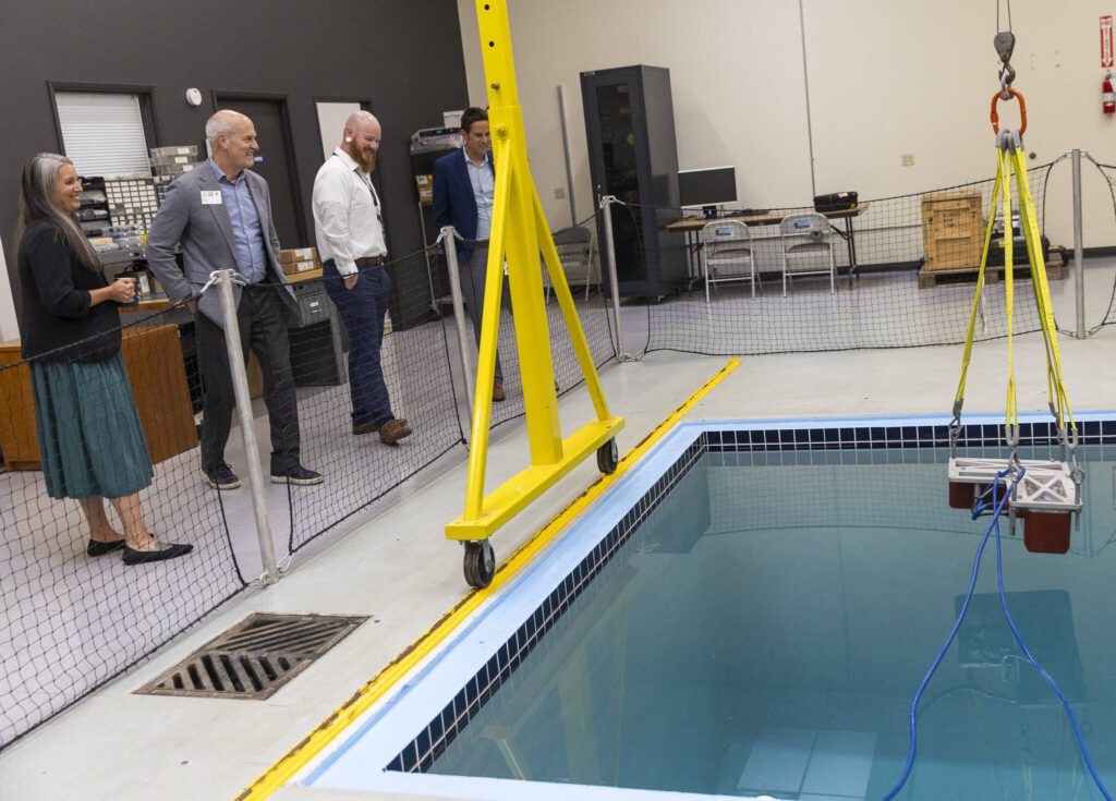 Vice President of Customer Services Americas Stephanie Poole, Rep. Rick Larsen and Senior HSE and Facilities Manger Christian Stern look at an EM 2040 multi beam echo sounder hanging over a pool inside Kongsberg’s facility on Thursday, July 31, 2025 in Lynnwood, Washington. (Olivia Vanni / The Herald)
