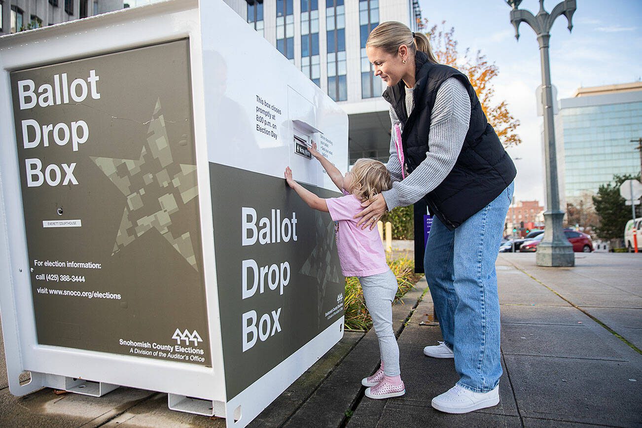 Carli Brockman lets her daughter Carli, 2, help push her ballot into the ballot drop box on the Snohomish County Campus during last year's general election in Everett. (Olivia Vanni / The Herald)