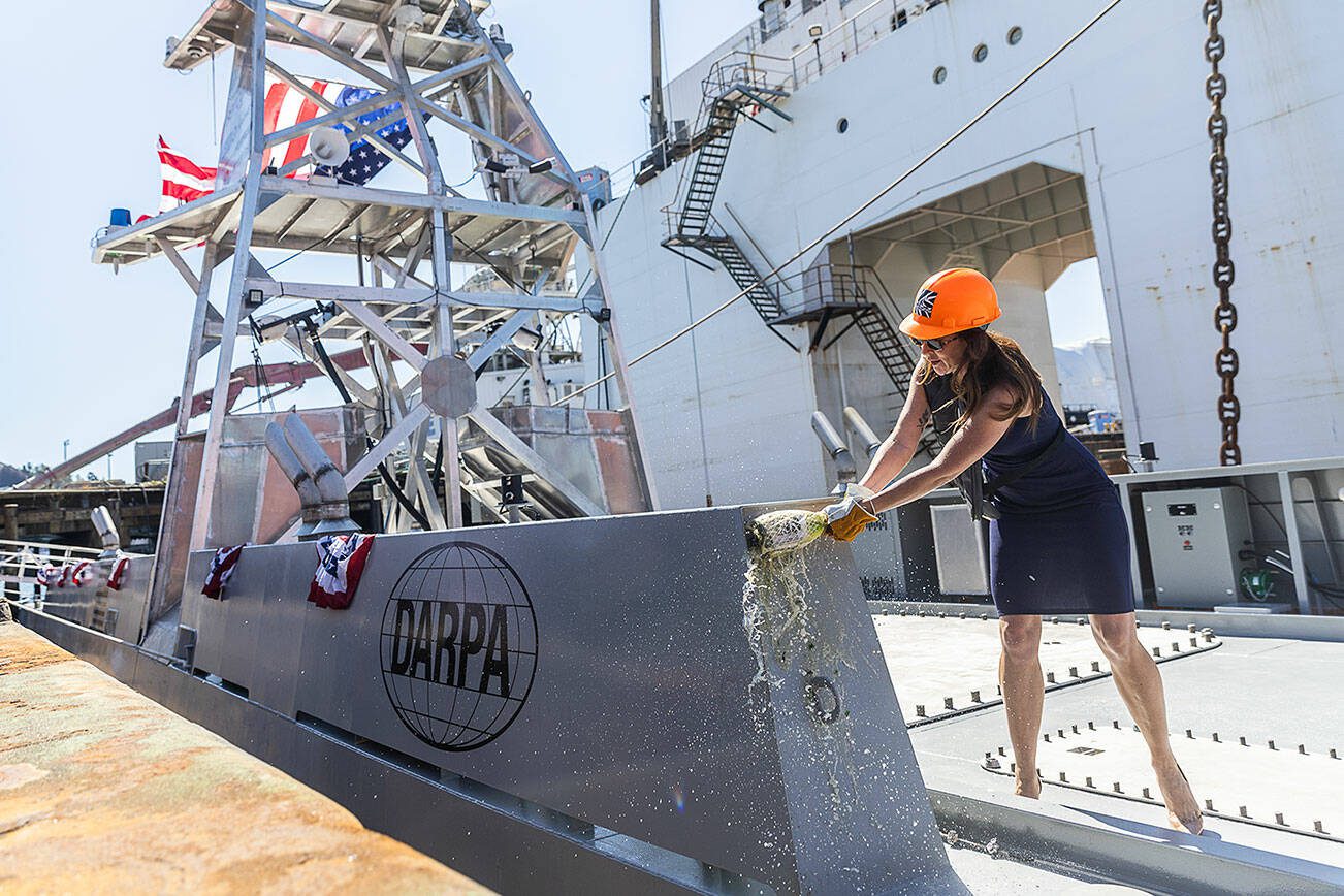 Mattie Hanley, wife of DARPA director Stephen Winchell, smashes a bottle to christen the USX-1 Defiant, first-of-its kind autonomous naval ship, at Everett Ship Repair on Monday, Aug. 11, 2025 in Everett, Washington. (Olivia Vanni / The Herald)