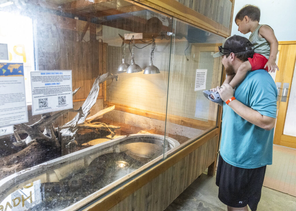 Elijah Tyler holds his son Giovanni, 2, as they look inside an enclosure on Aug. 19 in Monroe.
