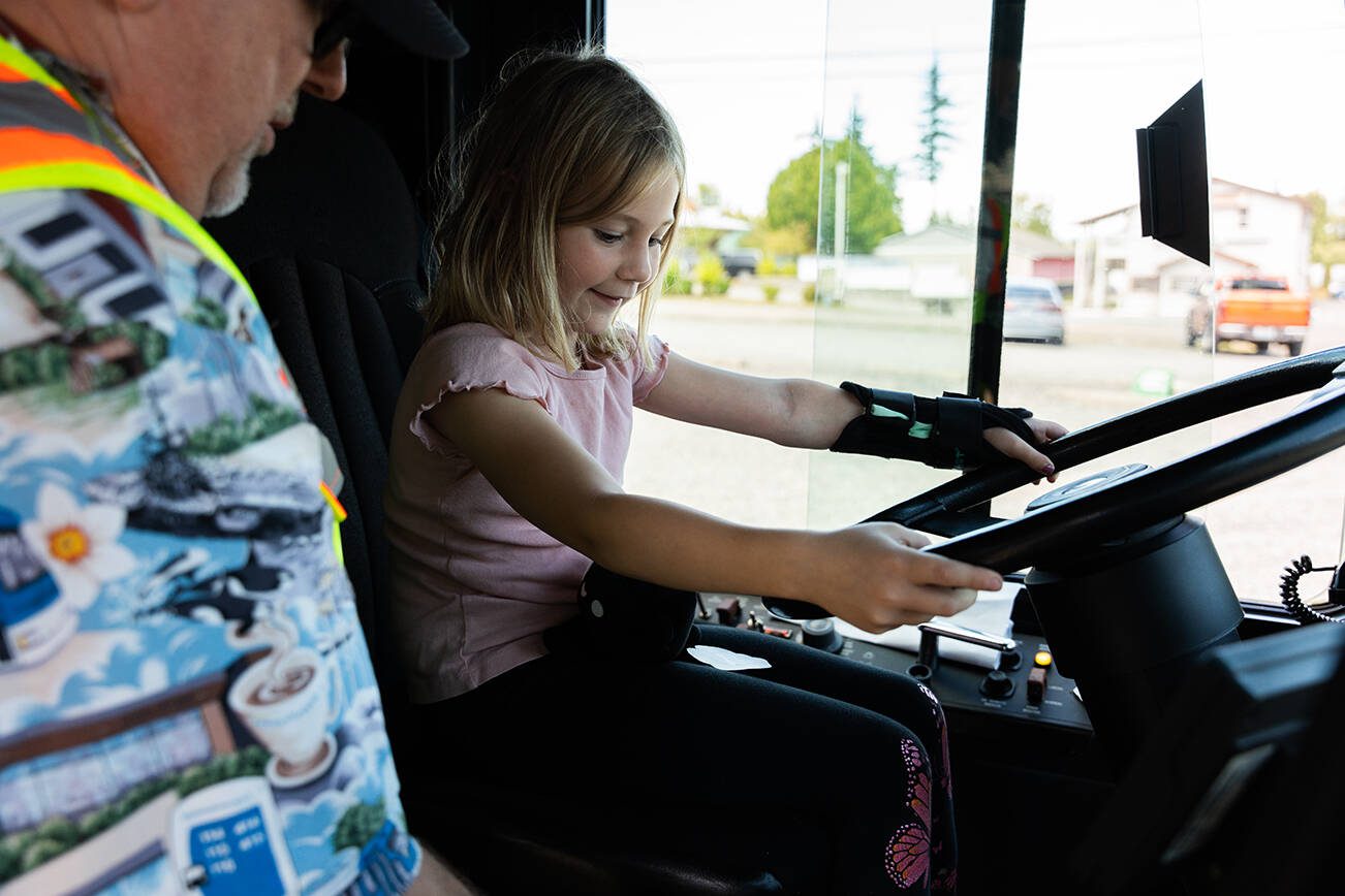 Kylie Brown, 7, grabs onto the wheel of a Community Transit bus during a 'Transit Tales' event on Wednesday, Aug. 20 in Smokey Point, Washington. (Will Geschke / The Herald)