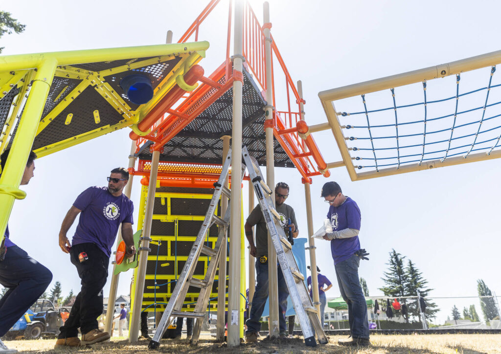 People from Northwest Playground and Community Creators work to assemble a new play structure at Marysville Middle School on Wednesday, Aug. 20, 2025 in Marysville, Washington. (Olivia Vanni / The Herald)
