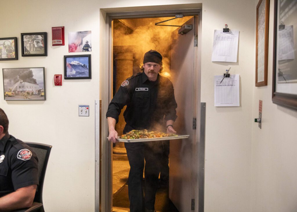 Ryan Fromm walks into the Everett fire station with a steaming tray of chicken and vegetables for dinner. (Olivia Vanni / The Herald)
Ryan Fromm walks into the Everett fire station with a steaming tray of chicken and vegetables for dinner. (Olivia Vanni / The Herald)
