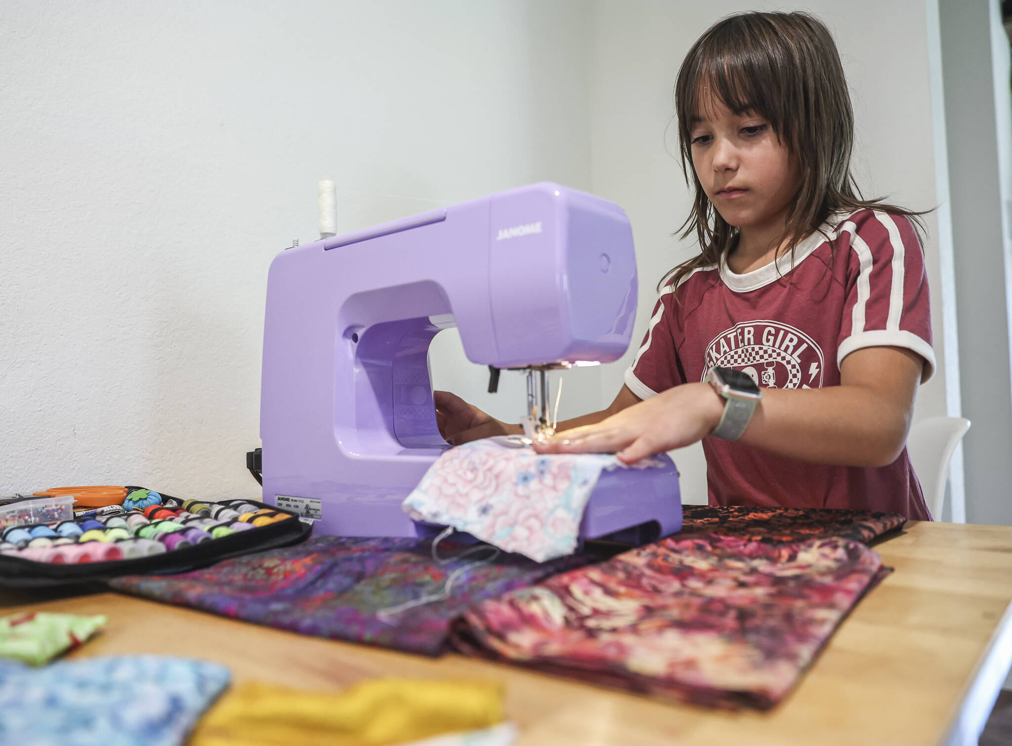Eisley Lewis, 9, demonstrates a basic stitch with her lavender sewing machine on Wednesday, Aug. 27, 2025 in Everett, Washington. (Olivia Vanni / The Herald)