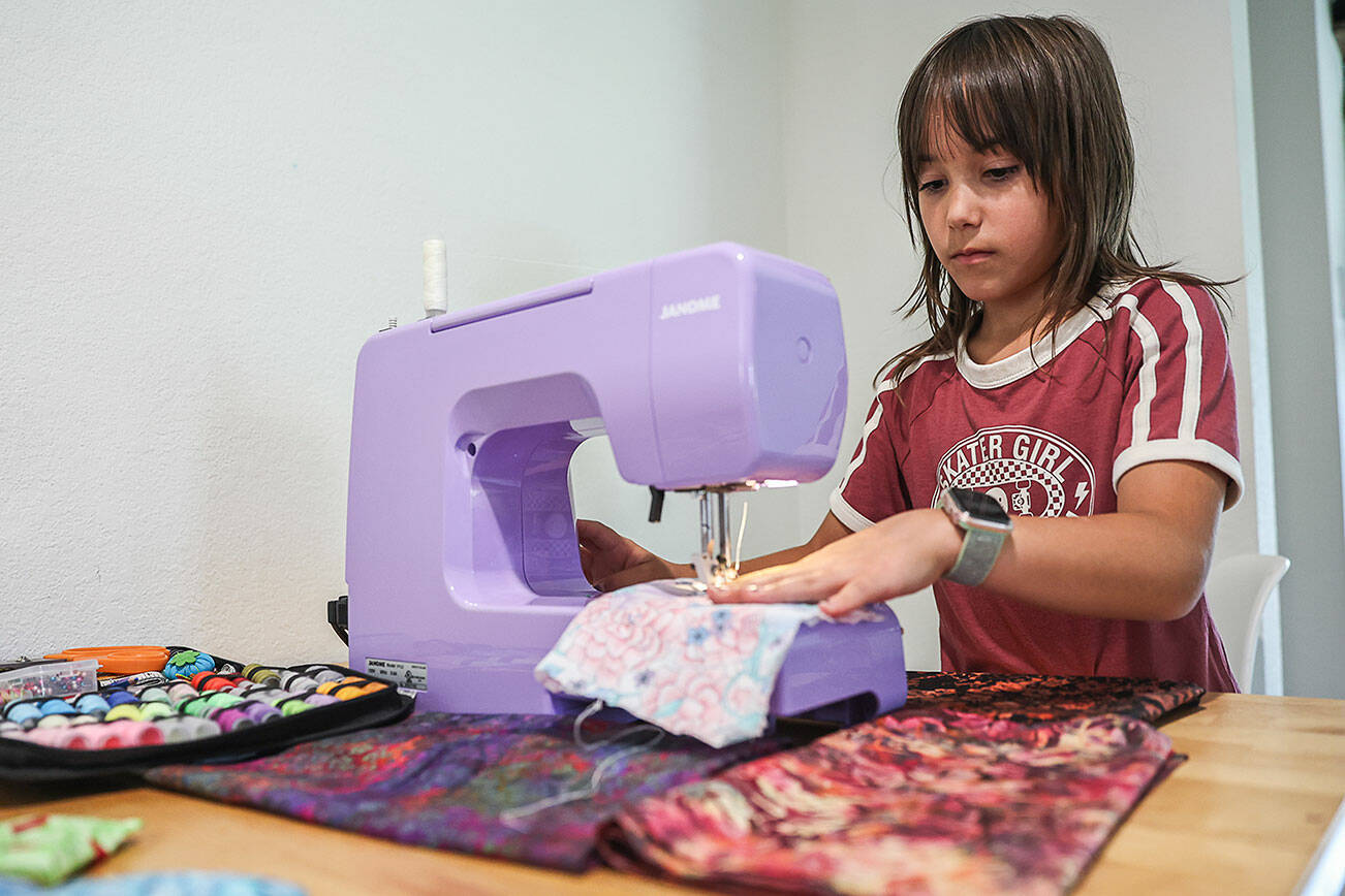Eisley Lewis, 9, demonstrates a basic stitch with her lavender sewing machine on Wednesday, Aug. 27, 2025 in Everett, Washington. (Olivia Vanni / The Herald)