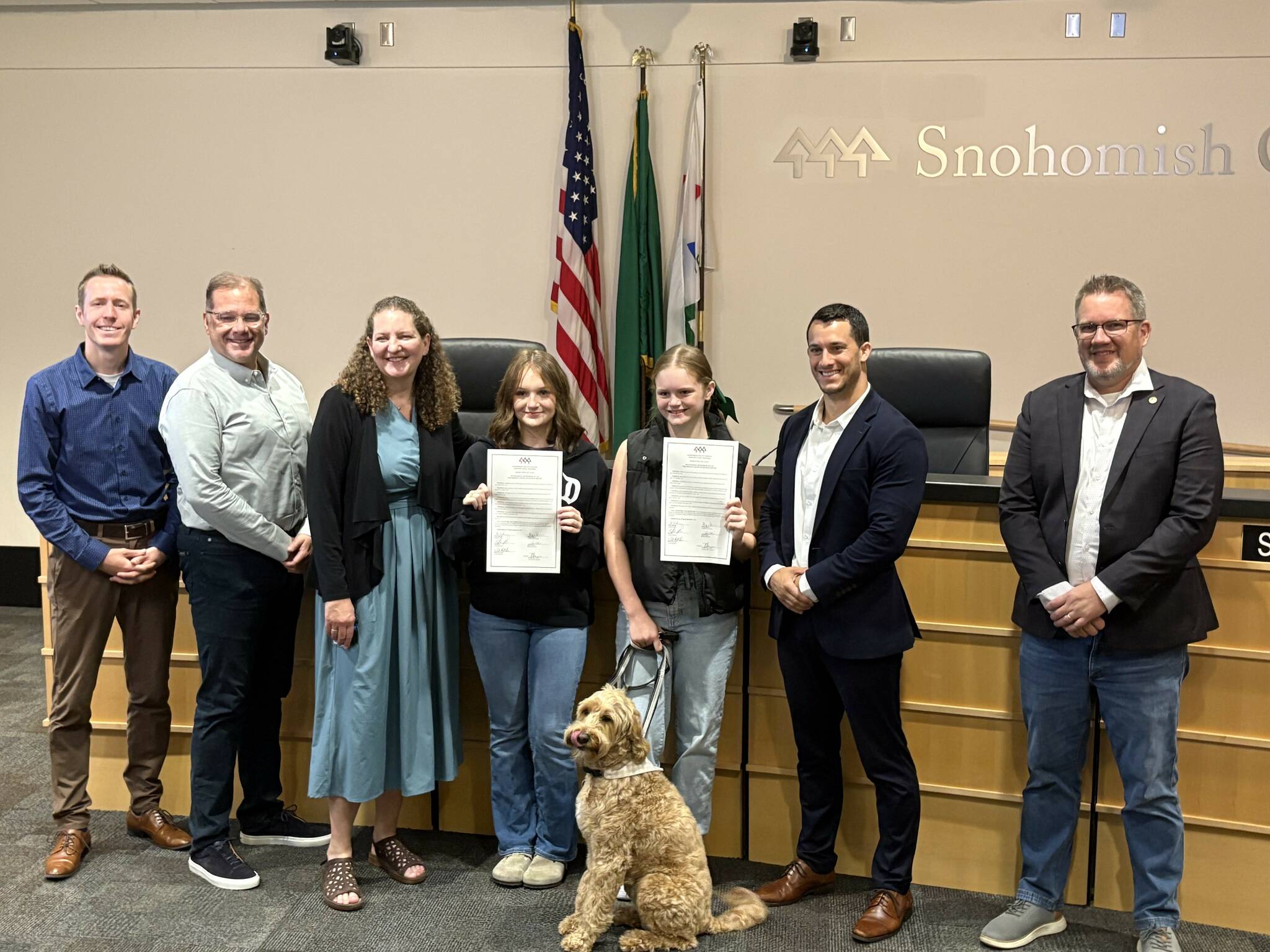 Taylor Scott Richmond
From left, County Council members Nate Nehring, Strom Peterson and Megan Dunn stand with Ella Estes and Reese Estes, their dog Cooper and council members Jared Mead and Sam Low after September 2025 was recognized as Childhood Cancer Awareness Month in Snohomish County on Tuesday. Ella and Reese both hold signed copies of the resolution.