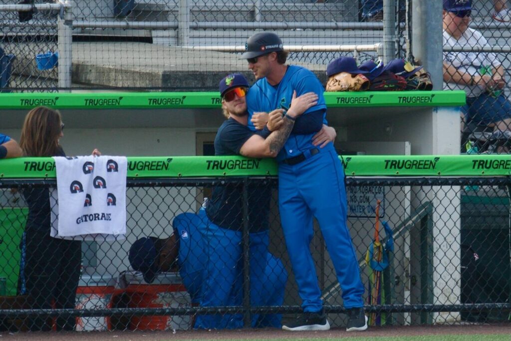 AquaSox outfielder Colin Davis embraces manager Zach Vincej from inside the dugout during Everett’s 7-5 win against Eugene at Funko Field on Aug. 31, 2025 (Joe Pohoryles / The Herald)

