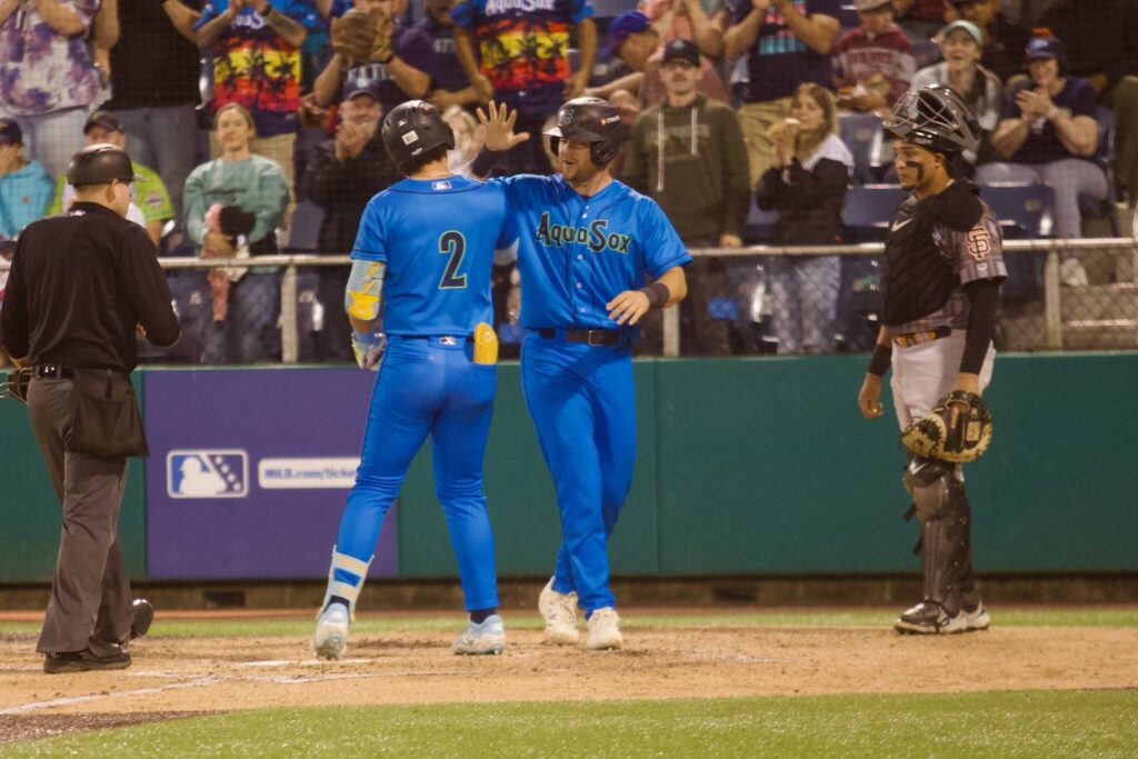 AquaSox catcher Matthew Ellis (right) greets third baseman Luis Suisbel at home plate following the latter’s go-ahead, two-run home run to help Everett beat the Eugene Emeralds 6-3 in Game 4 to clinch the 2025 Northwest League Championship at Funko Field on Sept. 13, 2025. (Joe Pohoryles / The Herald)
