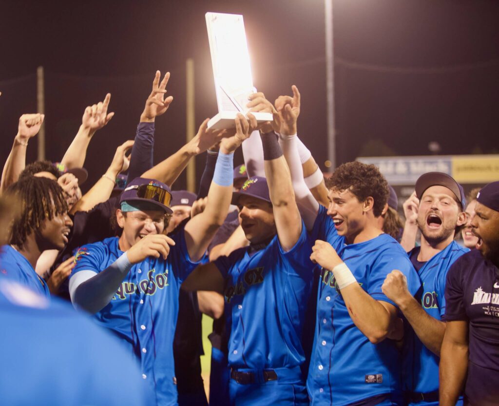AquaSox infielders Luis Suisbel (center, left) and Charlie Pagliarini (center, right) hoist the Northwest League Championship trophy as teammates celebrate around them following Everett’s series-clinching 6-3 win in Game 4 against the Eugene Emeralds at Funko Field on Sept. 13, 2025. (Joe Pohoryles / The Herald)
