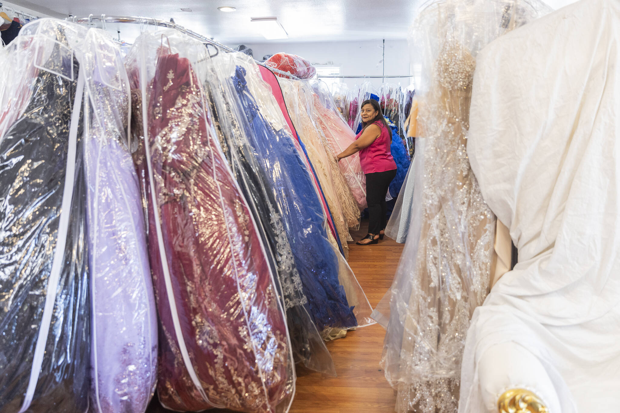 Lyda Herrera sorts through a large section of quinceañera dress in her store Las tres Beautifuls on Tuesday, July 15, 2025 in Everett, Washington. (Olivia Vanni / The Herald)