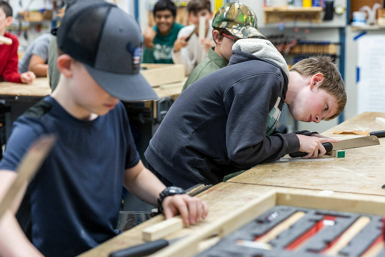 Silas Machin, 13, uses a hand saw to make a space for a fret to be placed during class on Oct. 7, 2025 in Lake Stevens, Washington. (Olivia Vanni / The Herald)