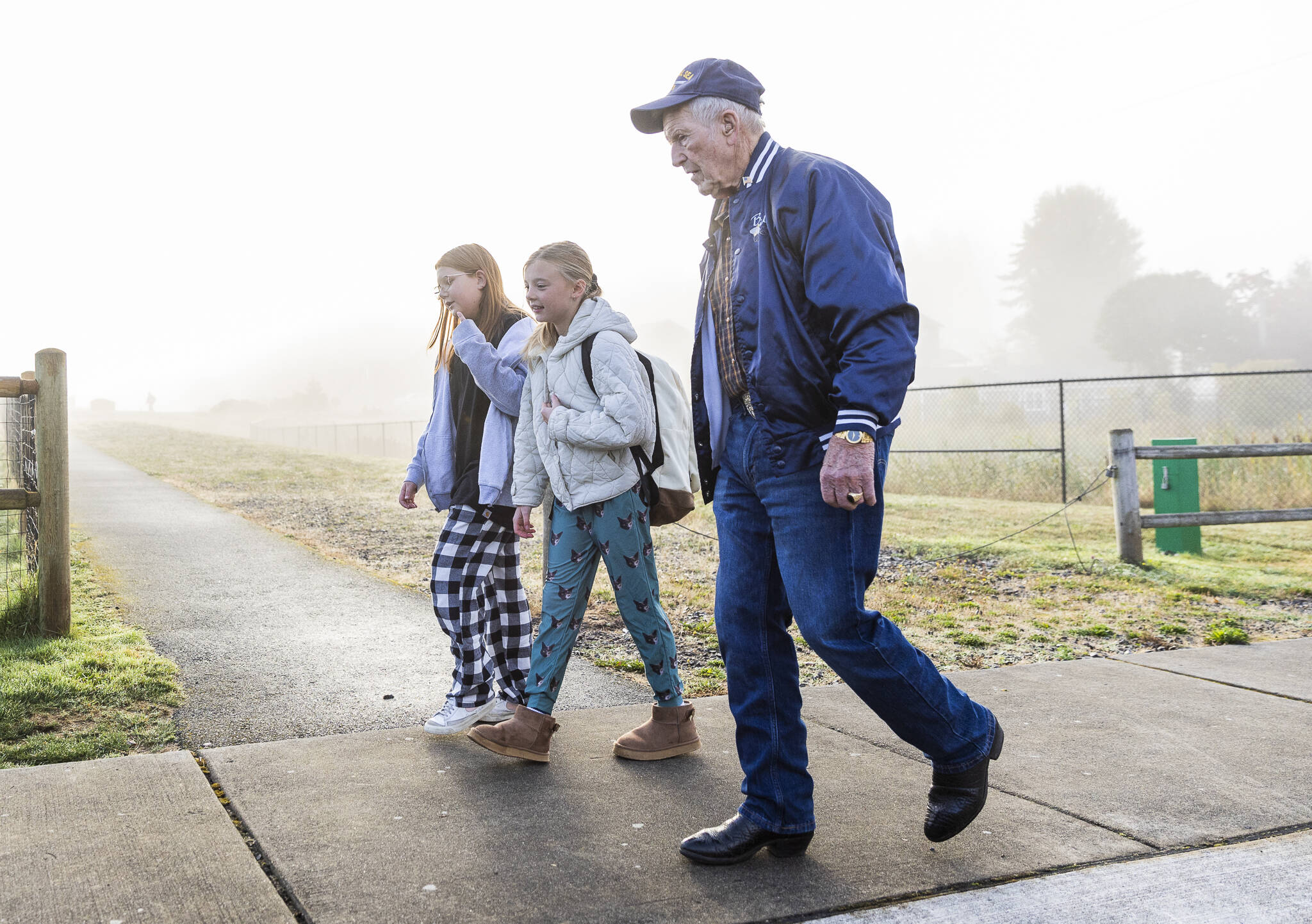 Otis Buzz Upton, 88, better known as Grandpa Buzz, walks with his great-granddaughter Teagan, 10, left, and her friend Indy Caskey, 10, center, on their way to school at Cascade View Elementary in Snohomish. (Olivia Vanni / The Herald)
