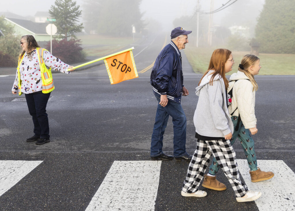 Grandpa Buzz smiles while he crosses the street and greets people along the way as he walks to Cascade View Elementary in Snohomish. (Olivia Vanni / The Herald)
