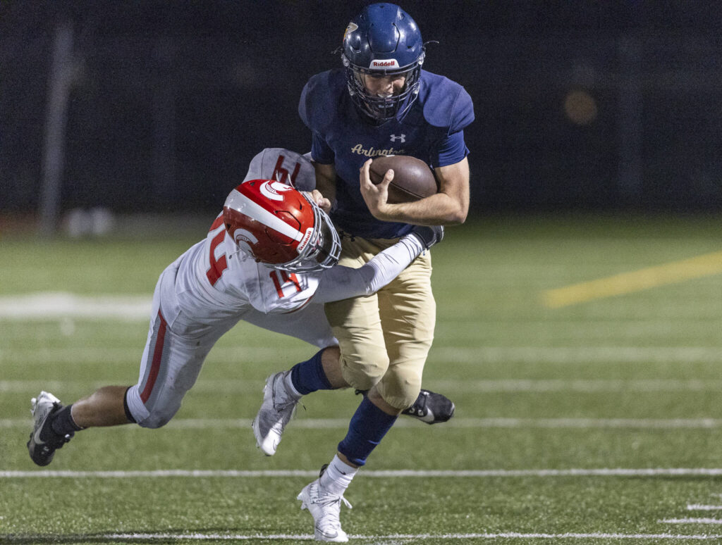 Arlington’s Kaleb Bartlett-Wood is tackled by Stanwood’s Michael Eagle during the game on Oct. 10, 2025 in Arlington, Washington. (Olivia Vanni / The Herald)
