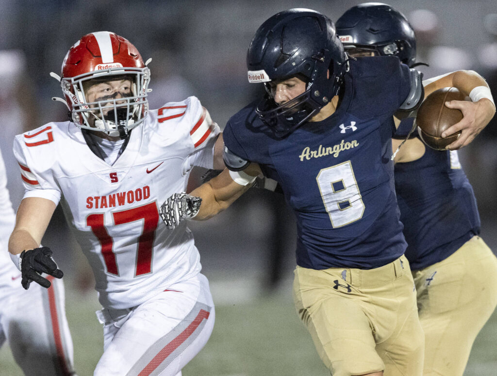 Arlington’s Linkin Currie runs with the ball as Stanwood’s Jake Simonson chases during the game on Oct. 10, 2025 in Arlington, Washington. (Olivia Vanni / The Herald)
