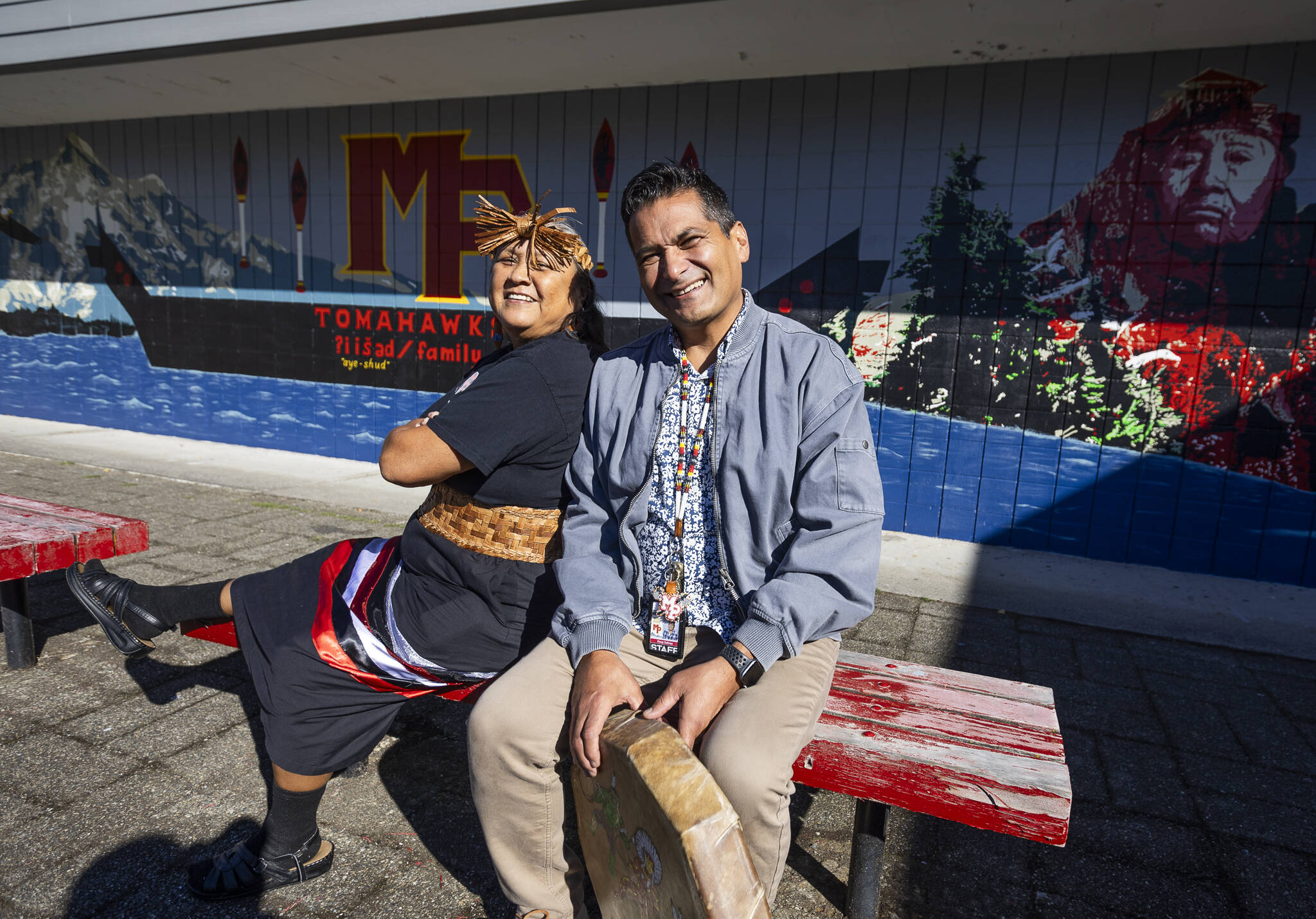 Marysville Pilchuck High School mural artists Monie Ordonia, left, and Doug Salinas, right, in front of their mural on the high school campus on Oct. 14, 2025 in Marysville, Washington. (Olivia Vanni / The Herald)