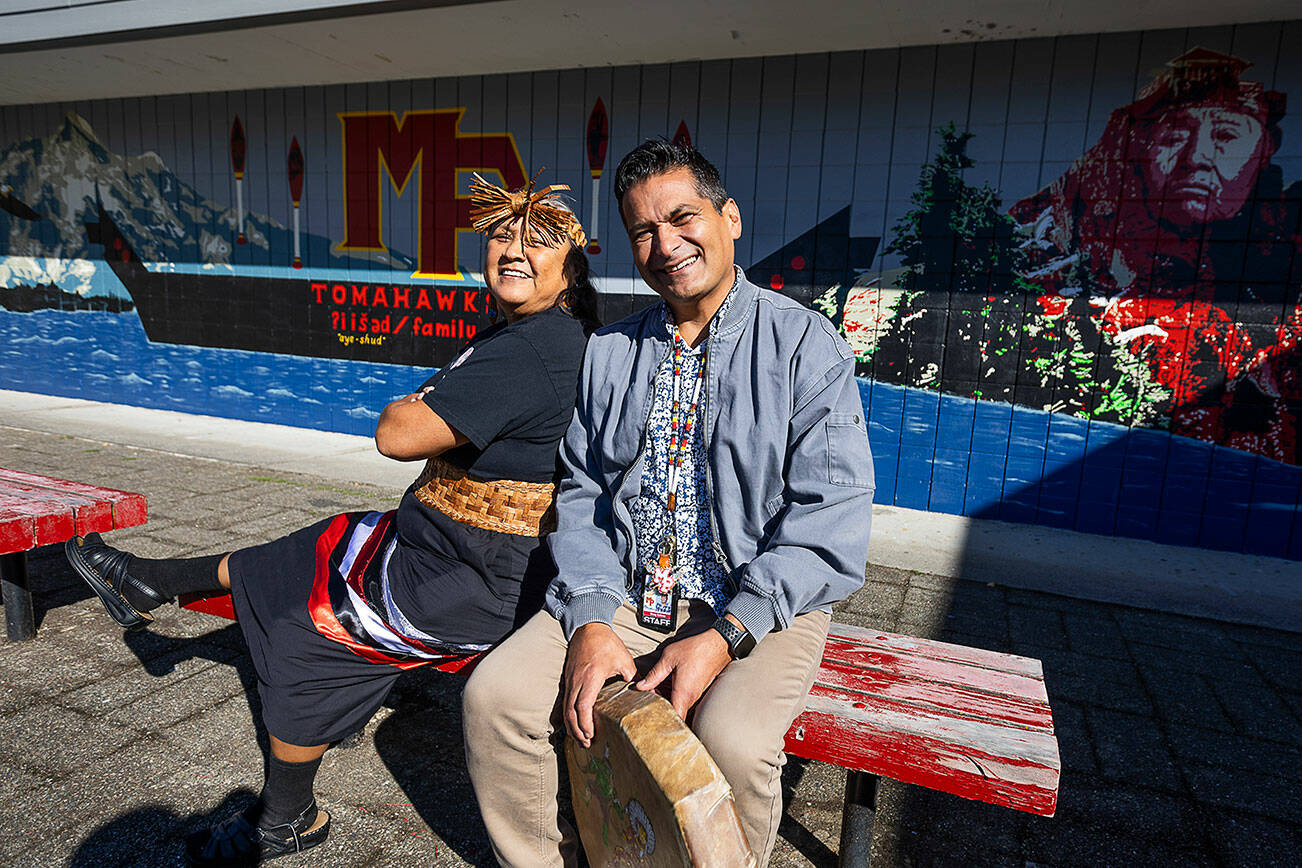 Marysville Pilchuck High School mural artists Monie Ordonia, left, and Doug Salinas, right, in front of their mural on the high school campus on Oct. 14, 2025 in Marysville, Washington. (Olivia Vanni / The Herald)