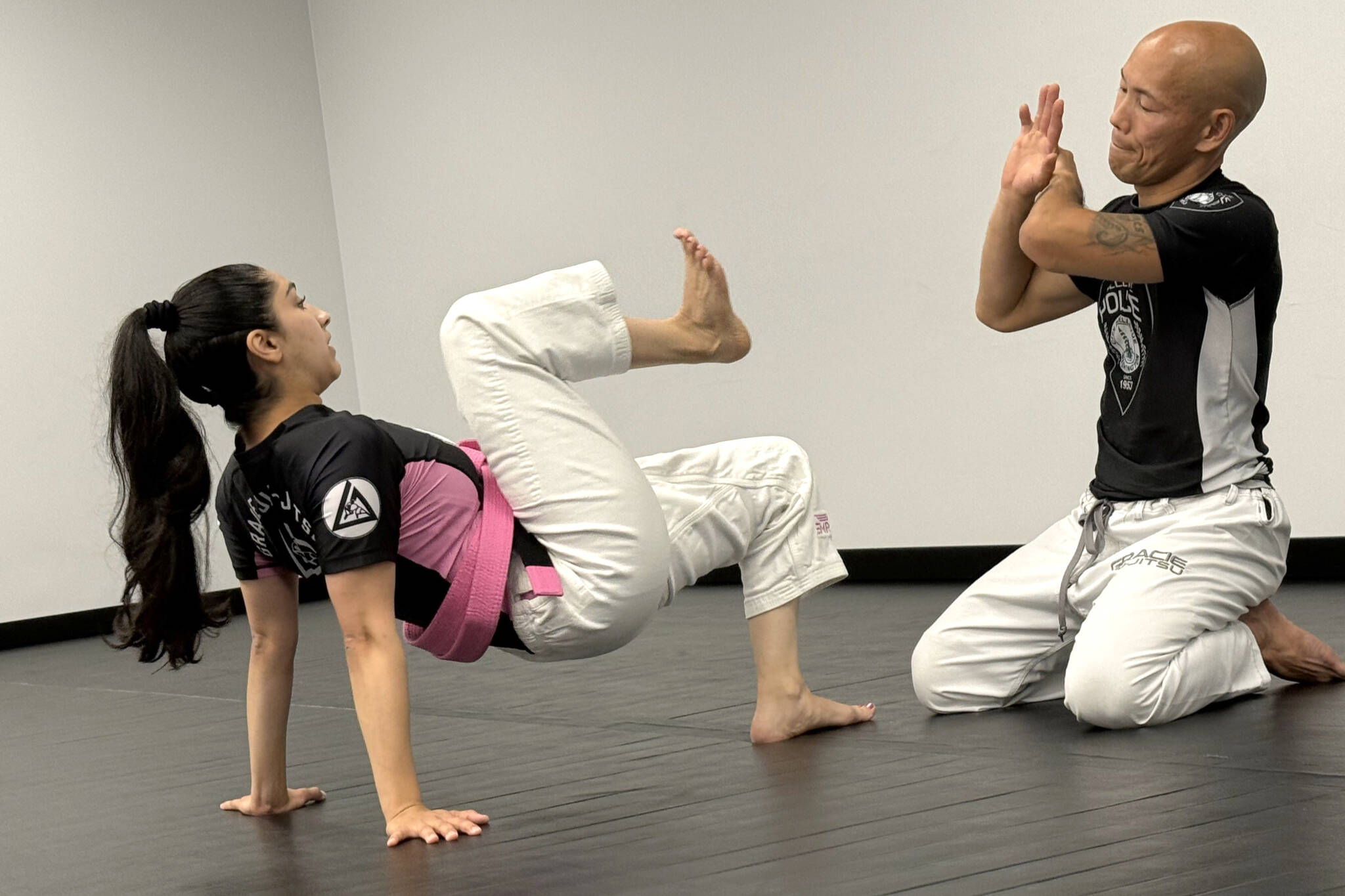 Lynnwood Officer Maryam McDonald demonstrates a guard get-up with Bellevue Officer Craig Hanaumi at PandaRoll JiuJitsu on Oct. 4 in Lynnwood. (Jenna Millikan / The Herald)