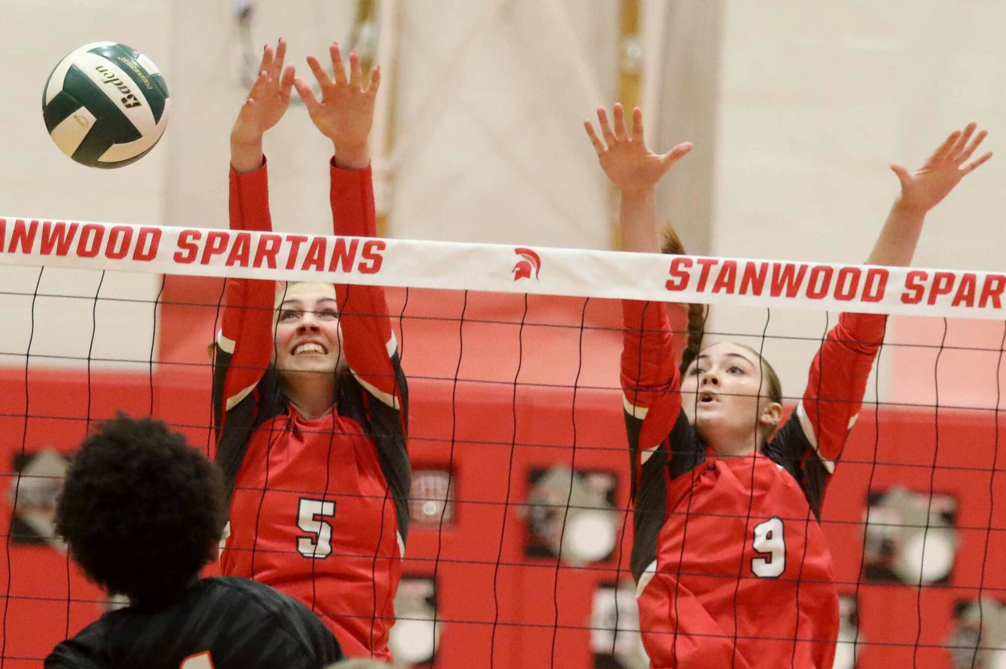 Stanwood junior setter Addison Bowie (No. 5) and junior middle blocker Presley Harris (No. 9) attempt to block Monroe sophomore Shannara Peebles’ hit during a District 1 3A quarterfinals match in Stanwood, Wash., on Tuesday, Nov. 12, 2024. The Spartans won 3-1. (Taras McCurdie / The Herald)