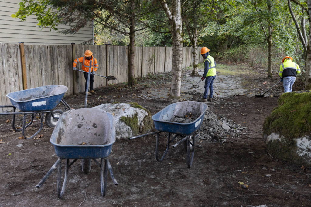 Workers shovel mud from a walking path on Greenleaf property that flowed down from the Eastview development on on Oct. 16, 2025 in Snohomish, Washington. (Olivia Vanni / The Herald)
