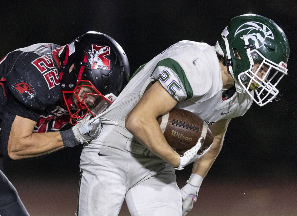 Edmonds-Woodway’s Gaige Lynch spits while he is tackled by Mountlake Terrace’s Owen Boswell during the game on Oct. 23, 2025 in Edmonds, Washington. (Olivia Vanni / The Herald)
