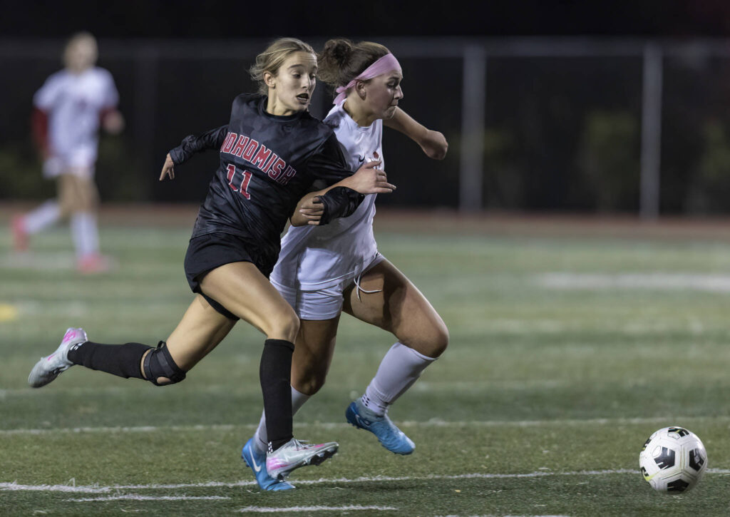 Snohomish’s Jenna Pahre and Stanwood’s Kayla Frydenlund grab each others arms as the run after the ball during the game on Oct. 27, 2025 in Snohomish, Washington. (Olivia Vanni / The Herald)