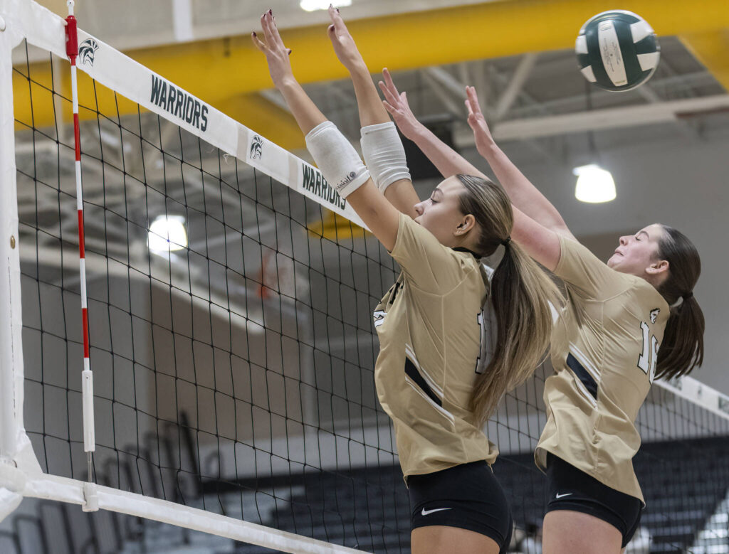 Lynnwood’s Evelyn Hall and Audrey Williams jump to block the ball during the game against Edmonds-Woodway on Oct. 29, 2025 in Edmonds, Washington. (Olivia Vanni / The Herald)

