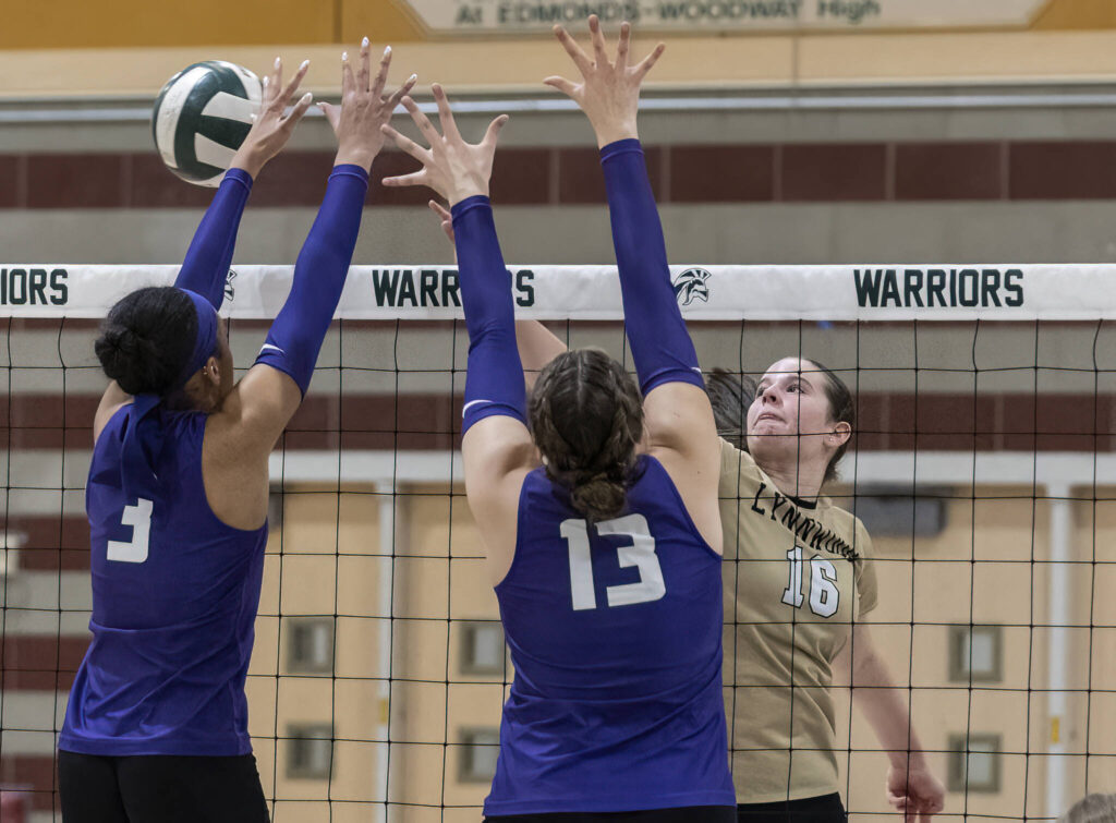 Lynnwood’s Audrey Williams tips the ball over the top of the net while Edmonds-Woodway’s Indira Carey-Boxley and Jillian Hatzenbeler block during the game on Oct. 29, 2025 in Edmonds, Washington. (Olivia Vanni / The Herald)
