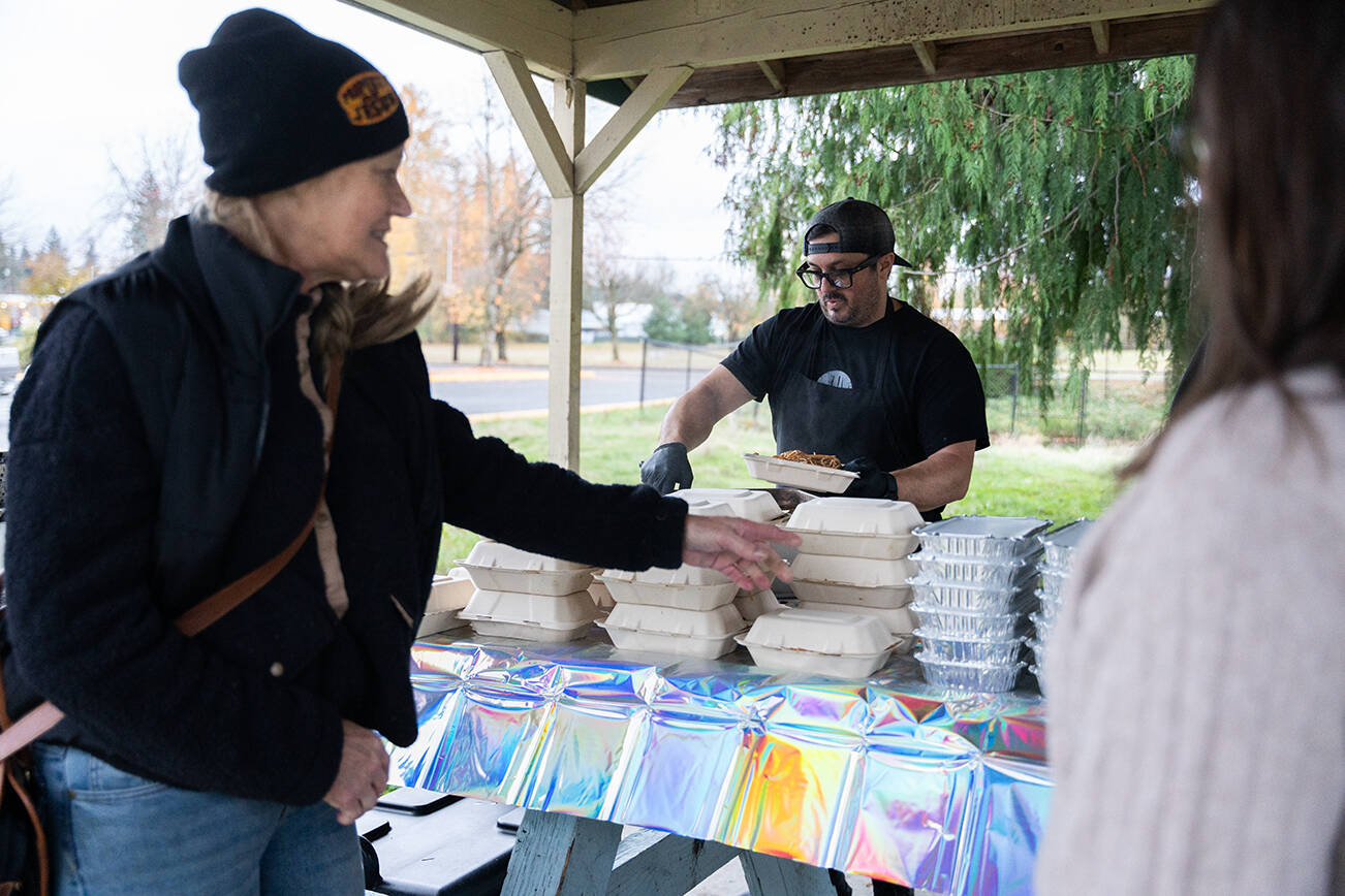 Alex Petrakopolos, center, helps distribute warm food to community members on Monday, Nov. 10 in Granite Falls, Washington. (Will Geschke / The Herald)