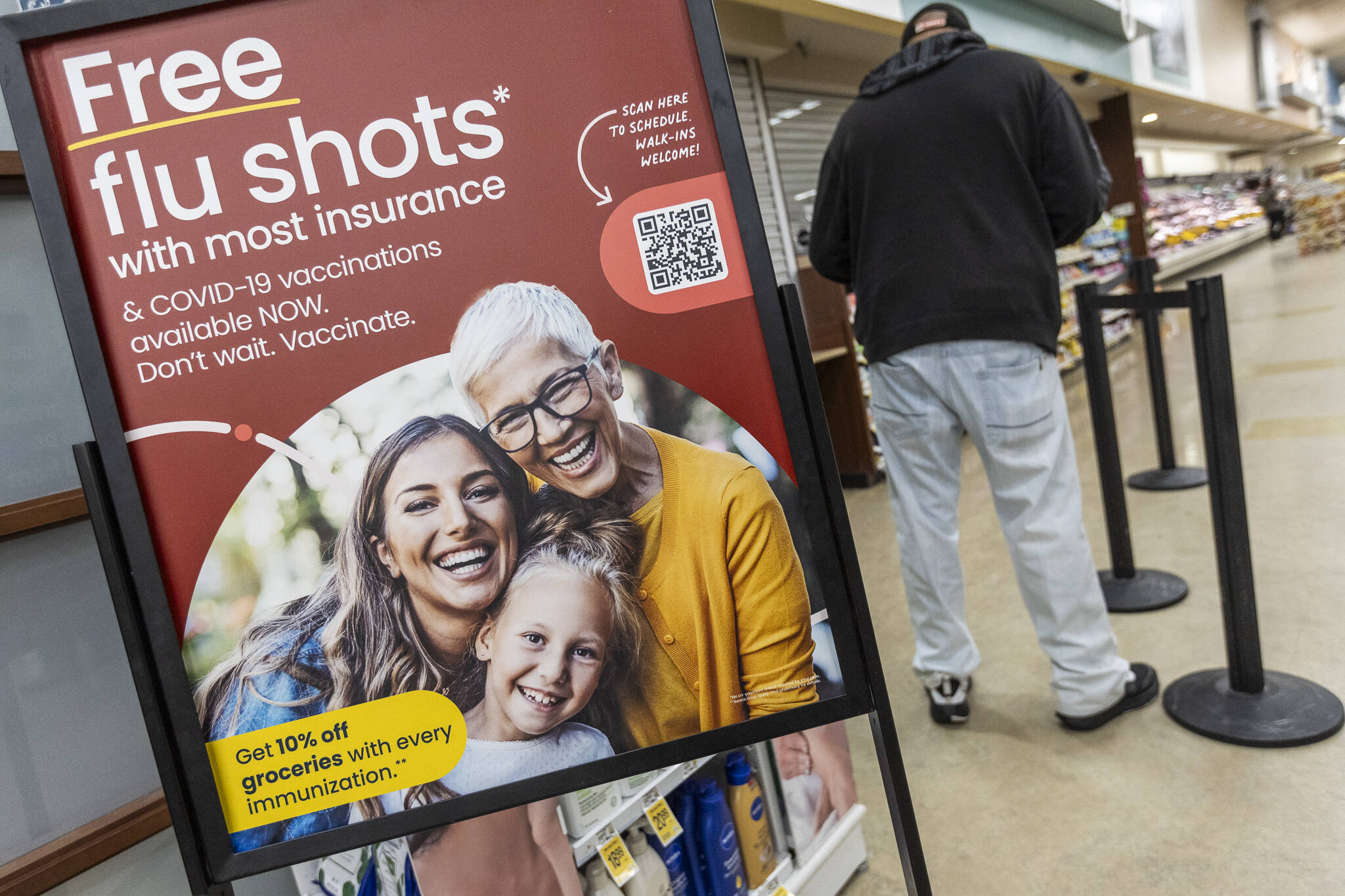 A person waits in line at a pharmacy next to a sign advertising free flu shots with most insurance on Thursday, Feb. 27, 2025 in Everett, Washington. (Olivia Vanni / The Herald)