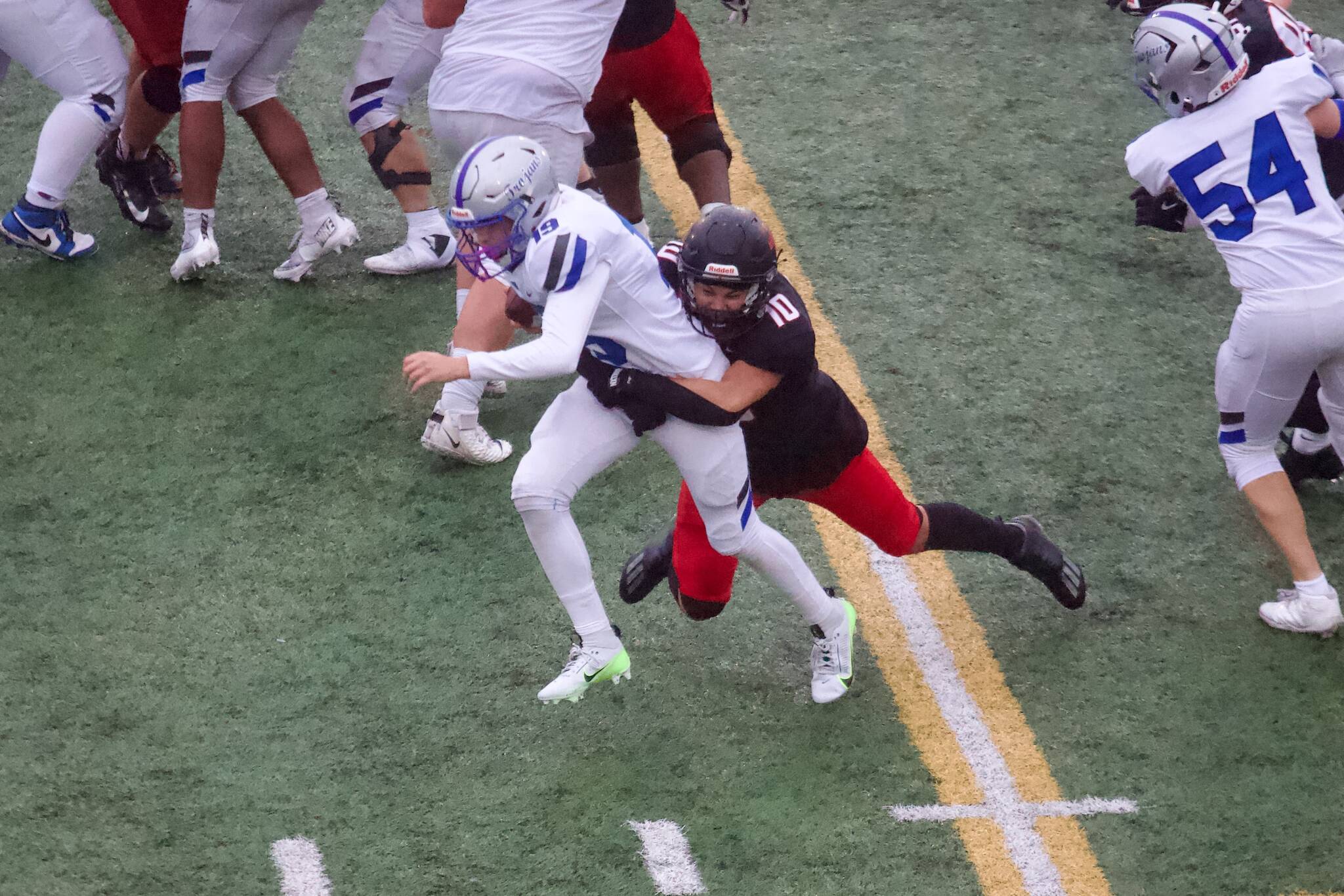 Archbishop Murphy senior Khian Mallang wraps up Olympic freshman Jordan Driskell in a tackle during the Wildcats' 45-13 win against the Trojans in the 2A State Round of 16 at Goddard Memorial Stadium on Nov. 15, 2025. (Joe Pohoryles / The Herald)