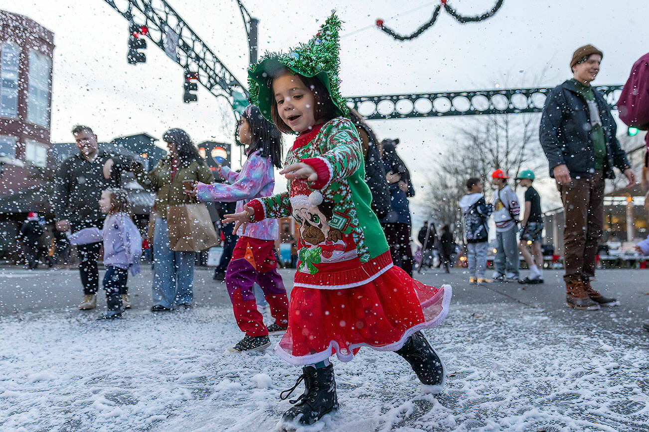 Charlie Rose Ziegler, 4, plays in fake snow in her Christmas themed outfit during Wintertide on Nov. 28, 2025 in Everett, Washington. (Olivia Vanni / The Herald)