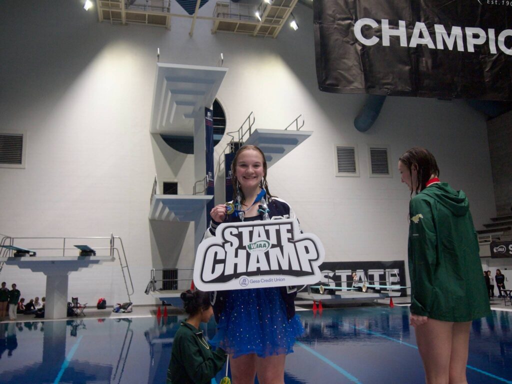 Claire Butler of Glacier Peak High School holds the State Champ sign after winning the Class 4A state 1-meter diving competition at the King County Aquatics Center in Federal Way, Washington on Saturday, Nov. 15, 2025. (Photo courtesy of Jolie Takano)
