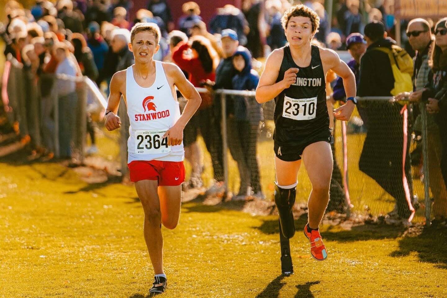 Arlington junior Ramon Little (right) runs alongside Stanwood's Max Grennell during the WIAA Cross Country State Championships at Sun Willows Golf Course in Pasco on Nov. 8, 2025. Little won the ambulatory championship in 12:29.2 on the 2.1-mile course, while Grennell competed as a partner in the unified race, which happened concurrently with the ambulatory race. (Photo courtesy Krissy Kolbeck / Arlington Cross Country / WIAA).
