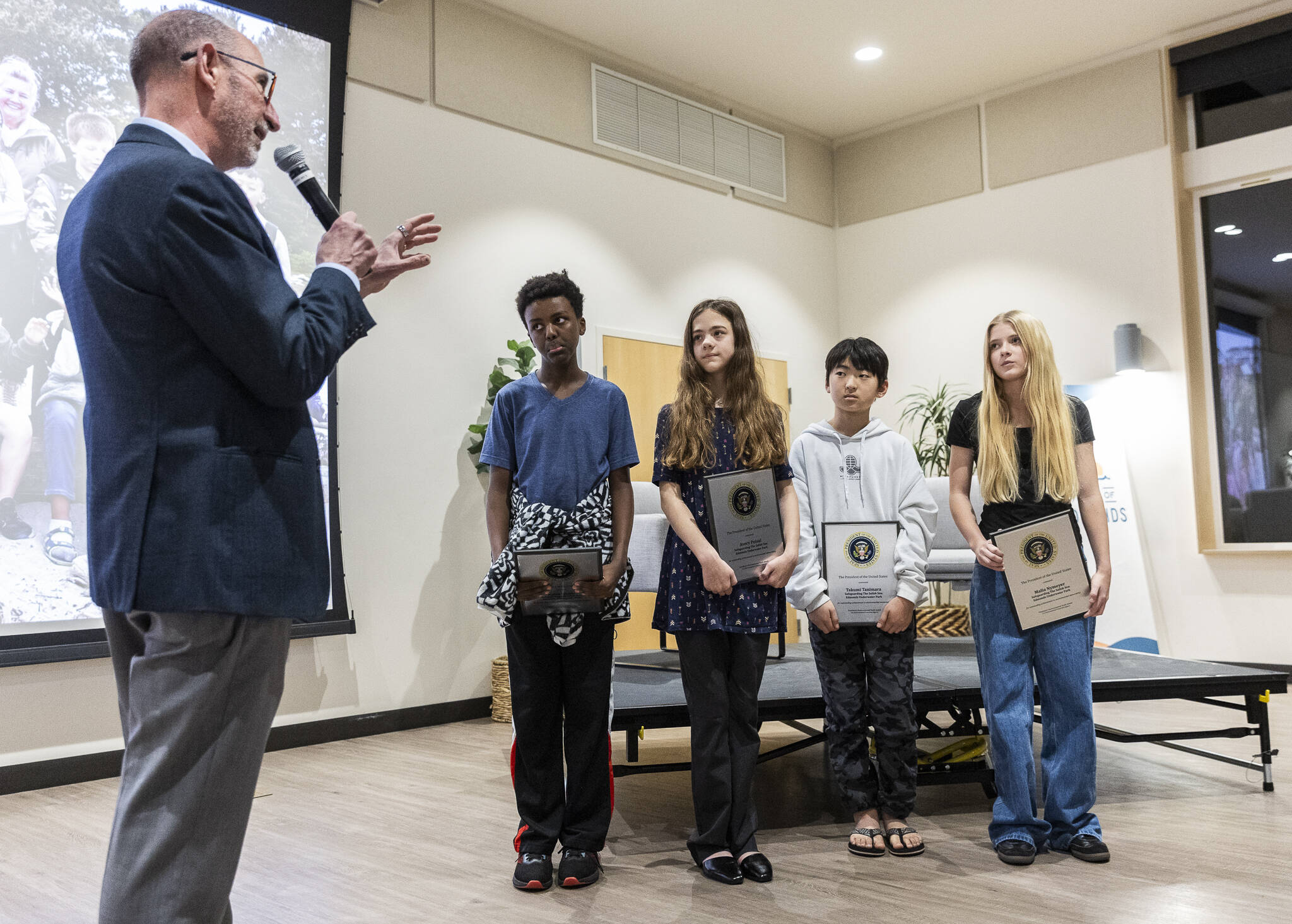 Edmonds Mayor Mike Rosen congratulates Kaleb Wolde (left to right), Avery Postal, Takumi Tanimara and Malia Nymeyer, on winning the President’s Environmental Youth Award that recognizes outstanding K-12 youth environmental stewardship projects across the nation on Nov. 20, 2025 in Edmonds, Washington. (Olivia Vanni / The Herald)