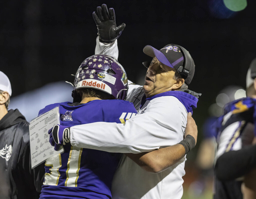 Lake Stevens head coach Tom Tri hugs Lake Stevens’ Kenny Buckmiller during the 4A state football quarterfinal game against Moses Lake on Nov. 22, 2025 in Lake Stevens, Washington. (Olivia Vanni / The Herald)
