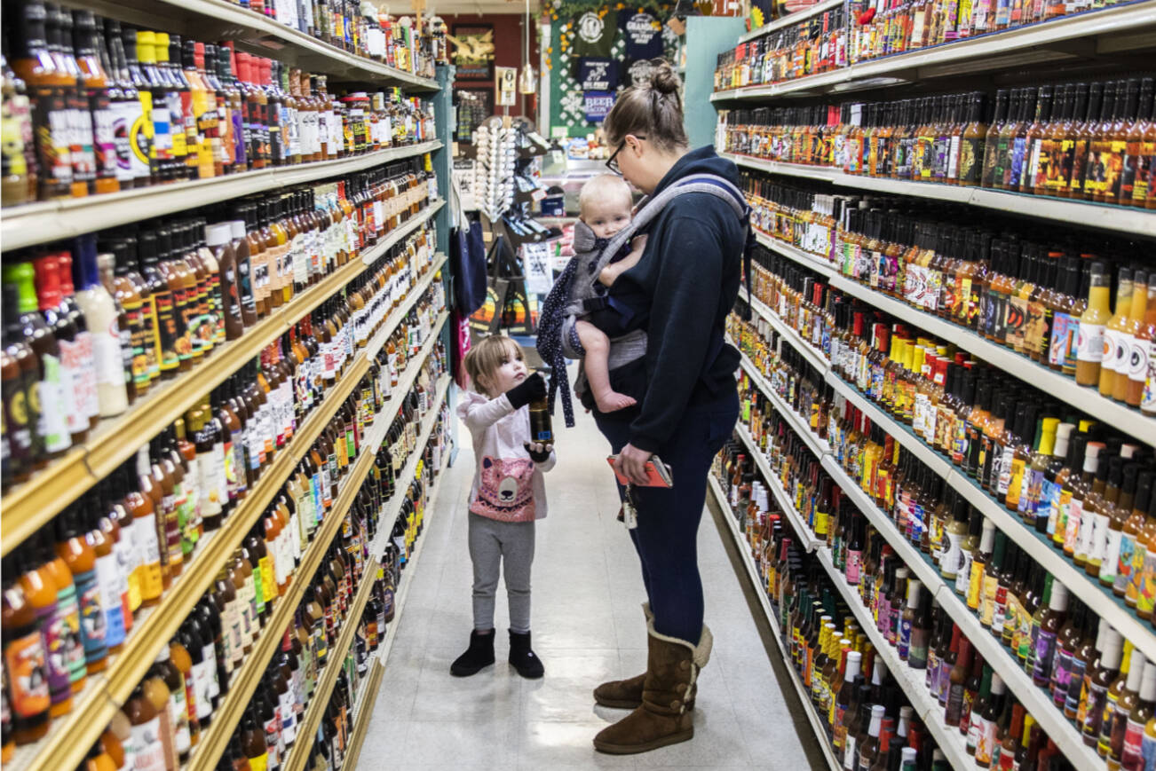 Elizabeth Ferrari, left, hands her mom Noelle Ferrari her choice of hot sauce from the large selection at Double DD Meats on Wednesday, Jan. 11, 2023 in Mountlake Terrace, Washington. (Olivia Vanni / The Herald)