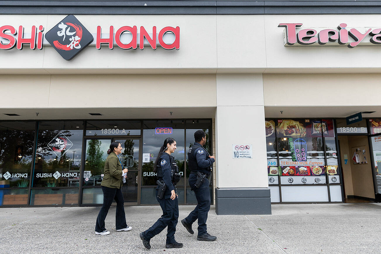Lynnwood Police Officers AJ Burke and Maryam McDonald with the Community Health and Safety Section Outreach team and City of Lynnwood’s Business Development Program Manager Simreet Dhaliwal Gill walk to different businesses in Alderwood Plaza on Wednesday, June 25, 2025 in Lynnwood, Washington. (Olivia Vanni / The Herald)