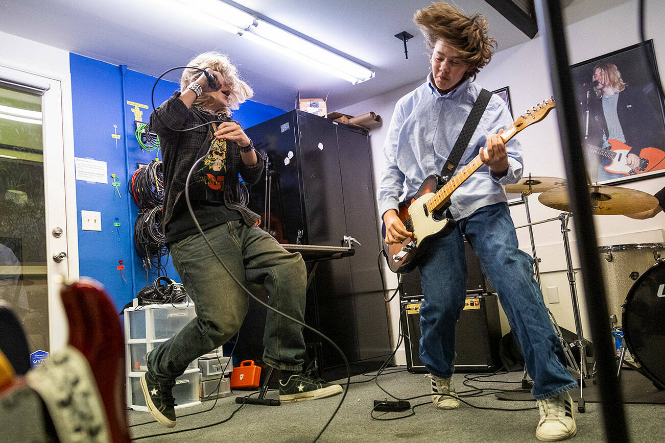 JJ Sobchuk, 14, left, and Owen Barton, 14, jump while doing a run through a set list during a group lesson at the Music Circle on Dec. 1, 2025 in Everett, Washington. (Olivia Vanni / The Herald)