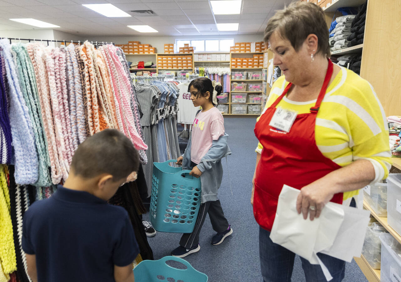 Aleen Alshamman (center) carries a basket as she picks out school clothes with the help of an Operation School Bell volunteer on Sept. 24 in Everett. Operation School Bell is an Assitance League of Everett program. (Olivia Vanni / The Herald file photo)