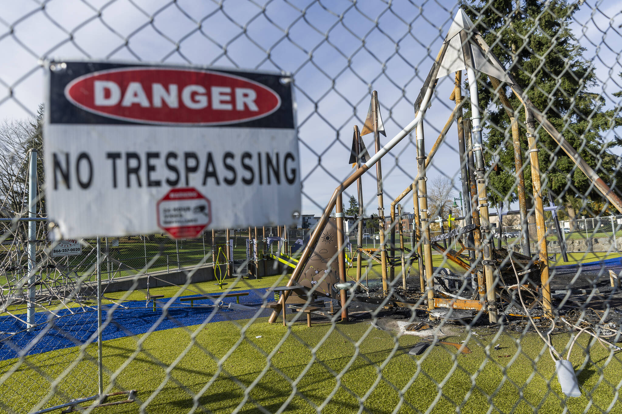A “danger” sign hangs on the fence surrounding the recently burned Wiggums Hollow playground on Nov 19 in Everett. (Olivia Vanni / The Herald)