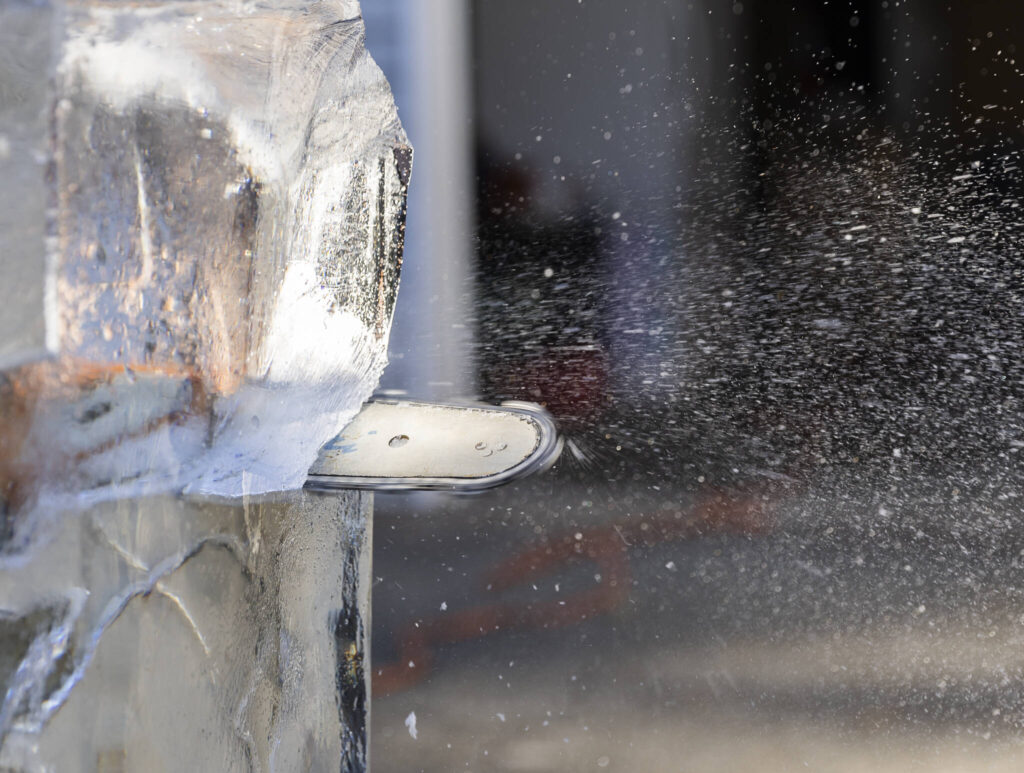 A chain saw sprays ice and water as Kitburi carves large ice chunks out of his sculpture on Sept. 17, 2025 in Marysville, Washington. (Olivia Vanni / The Herald)
