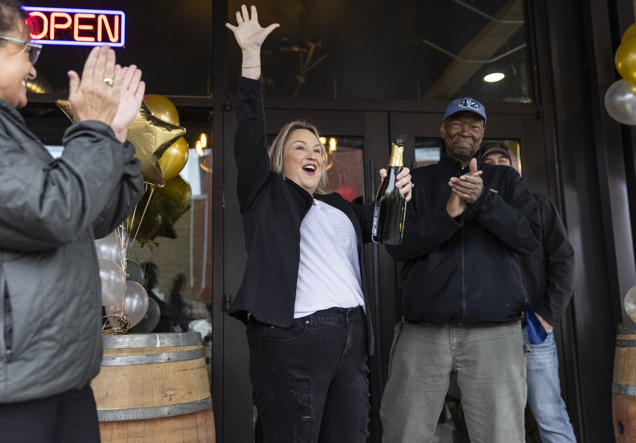 Kelsey Olson, the owner of the Rustic Cork Wine Bar, pops a bottle of champagne after cutting the ribbon for the opening on her new Rustic Cork location at the Port of Everett on Dec. 2, 2025 in Everett, Washington. (Olivia Vanni / The Herald)