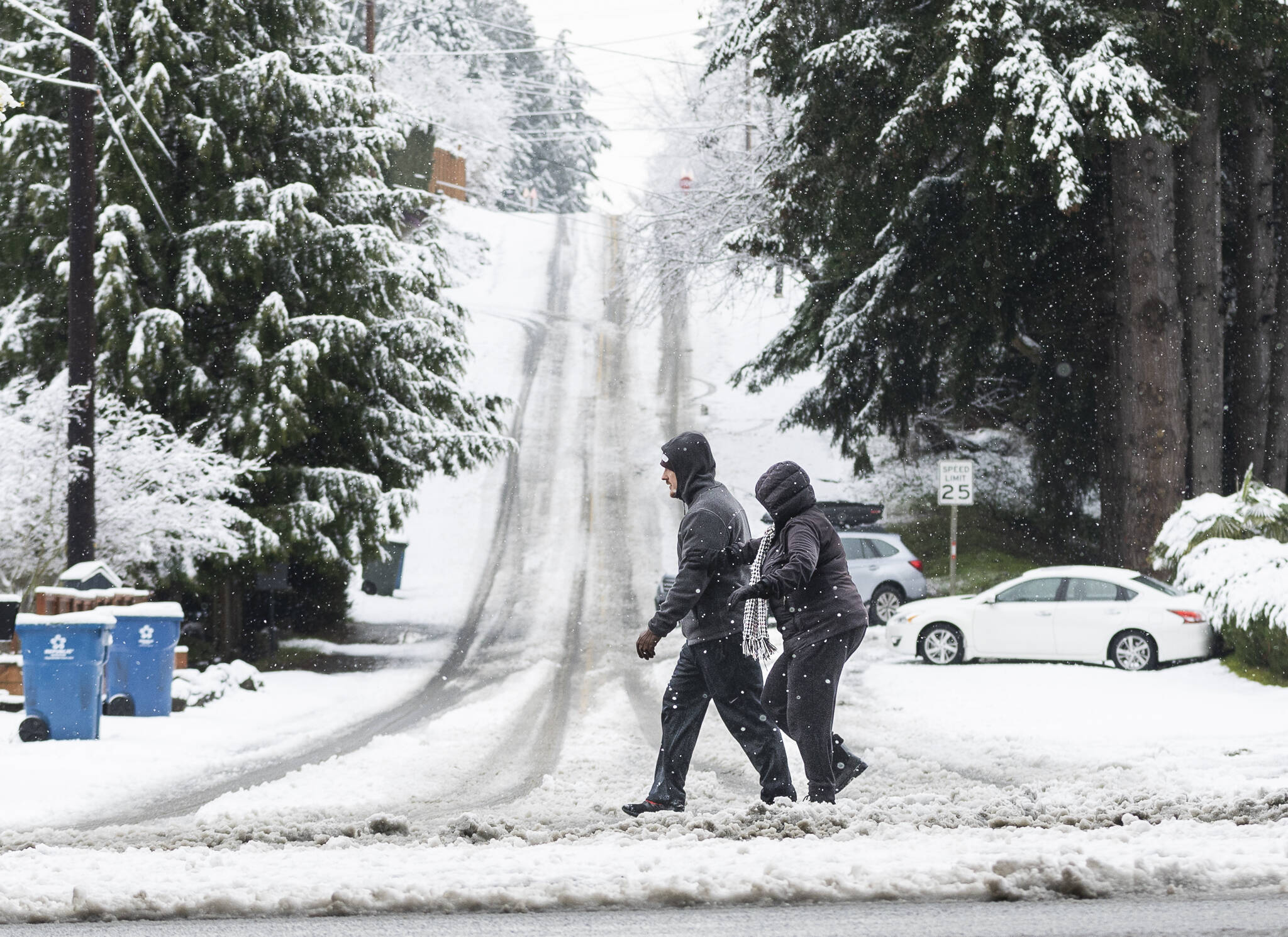 Pedestrians try to navigate the snow and slush covering the roads and sidewalks along 100th Avenue West on Thursday, Feb. 6, 2025 in Edmonds, Washington. (Olivia Vanni / The Herald)