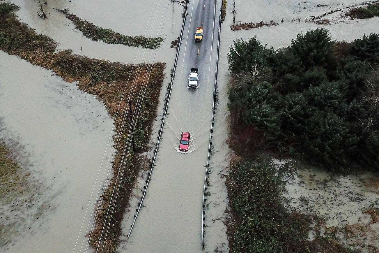 Drivers attempt to navigate floodwater from the Skykomish River covering Mann Road on Tuesday, Dec. 9, 2025 in Sultan, Washington. (Olivia Vanni / The Herald)
